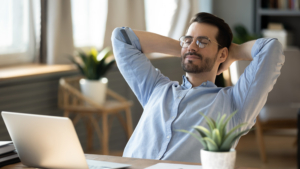 happy male-presenting office worker leaning back with eyes closed