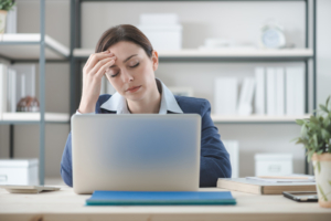 female-presenting office worker holding her head as though she has a headache